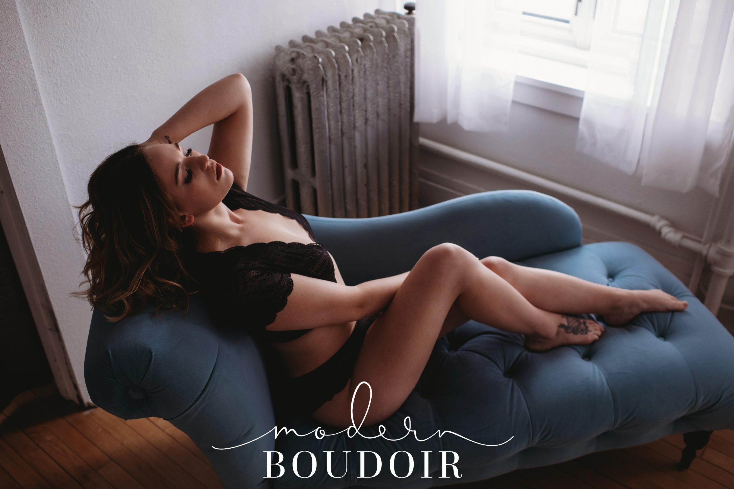 Woman posing in black lingerie on blue couch with Modern Boudoir in Iowa