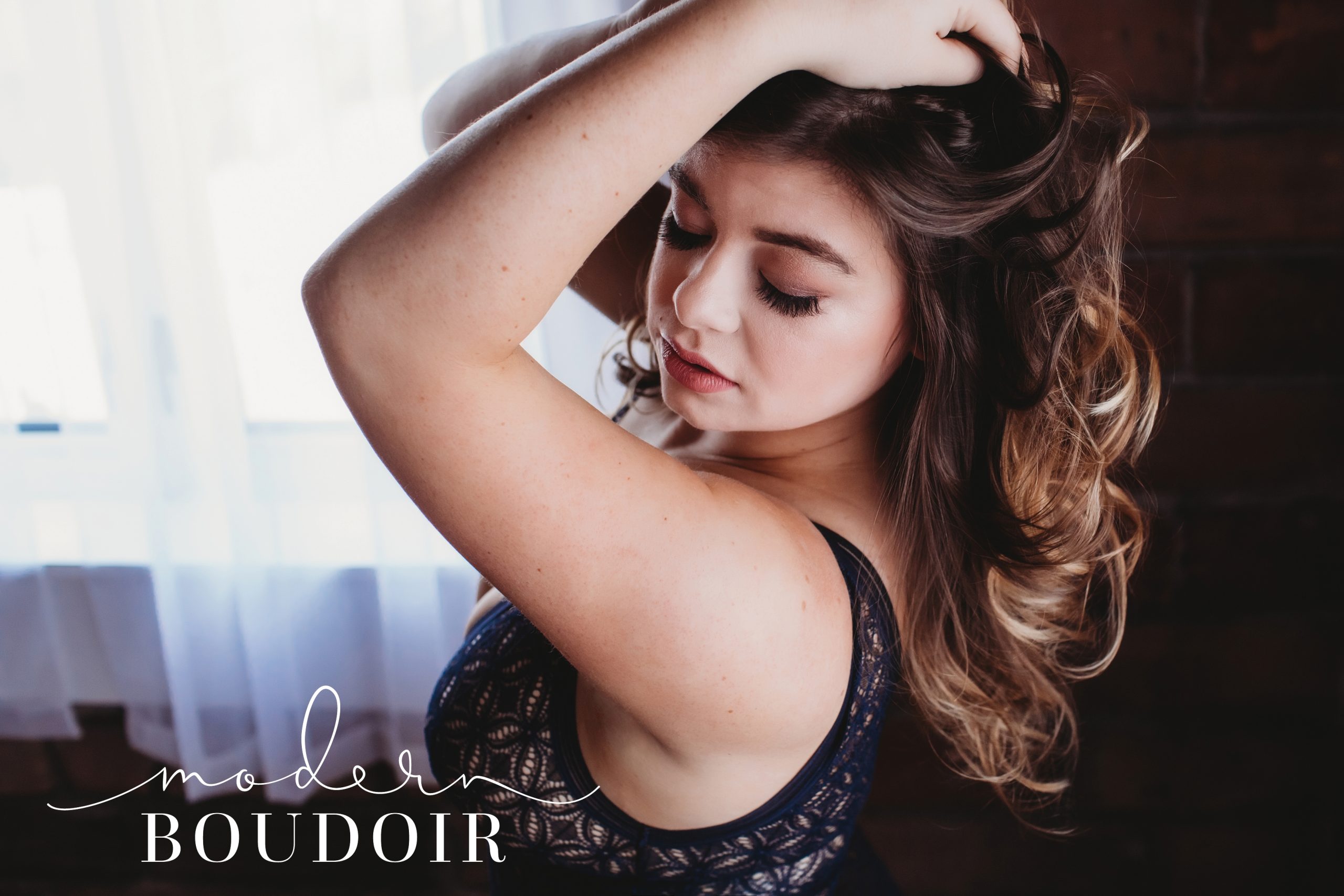 Woman with hands in curled hair modeling at Modern Boudoir in Iowa
