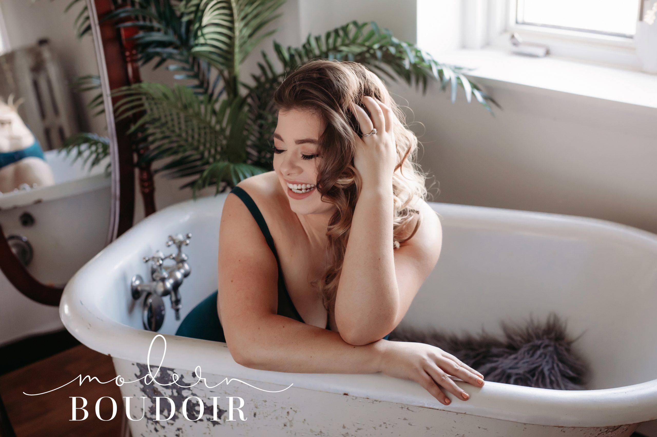 Woman laughing wearing bodysuit in a clawfoot tub at Modern Boudoir