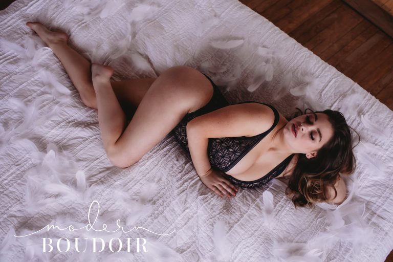 Woman laying on a bed posing at Modern Boudoir