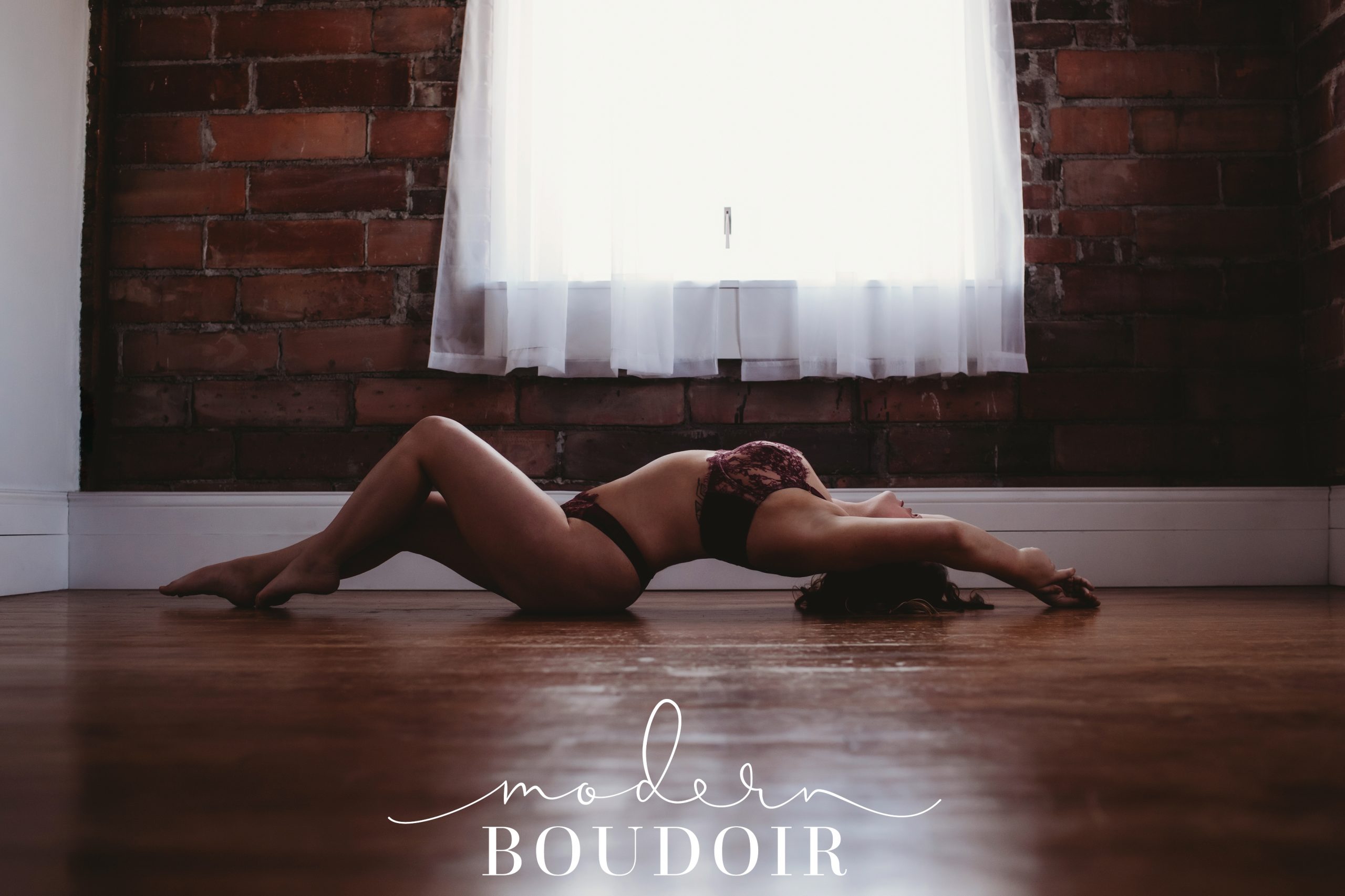 Woman posing by arching her back on the floor at Modern Boudoir in Boone, Iowa